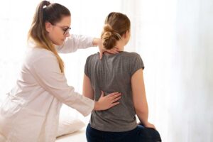 A chiropractor talking with a patient in a bright, welcoming exam room.