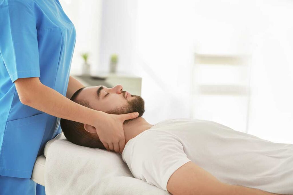 Person gently moving a knee while seated, with hands resting near the joint.